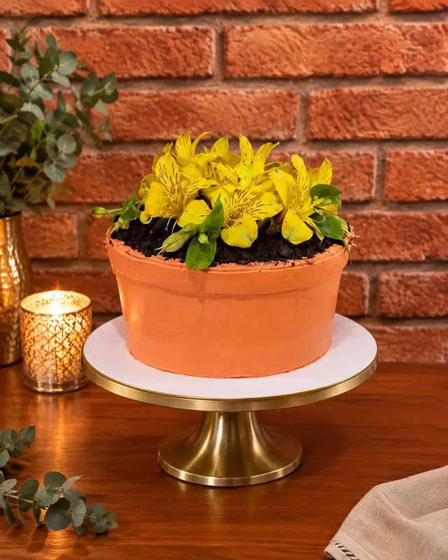 Bolo em formato de vaso de barro com flores amarelas no topo