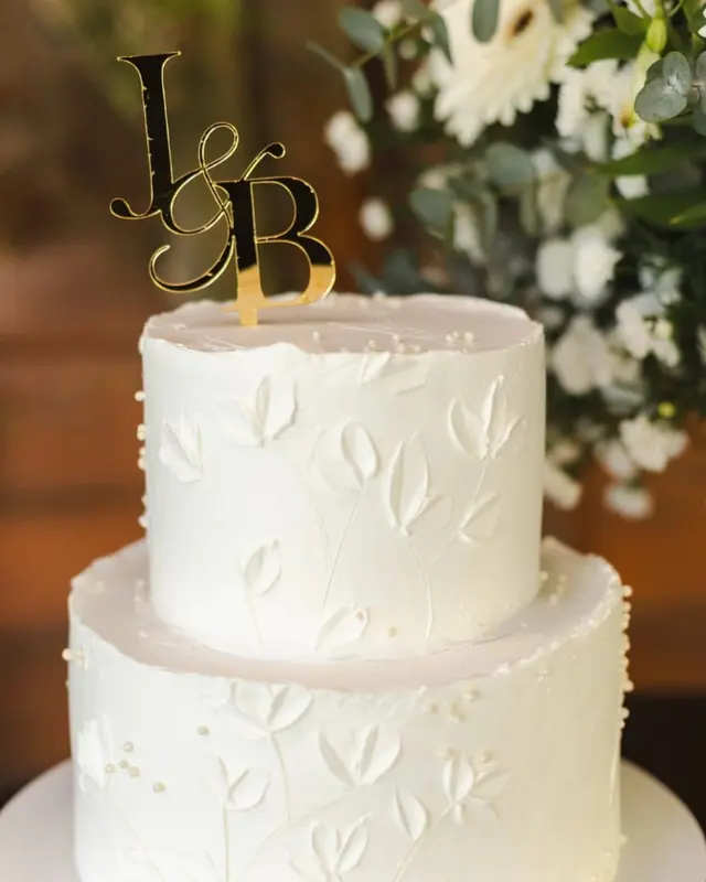 Bolo de casamento de dois andares, branco texturizado, com topo de iniciais