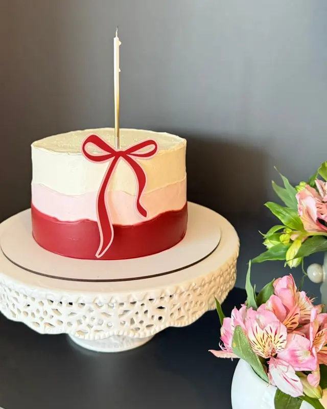 Bolo bicolor vermelho e branco com laço vermelho e vela acesa