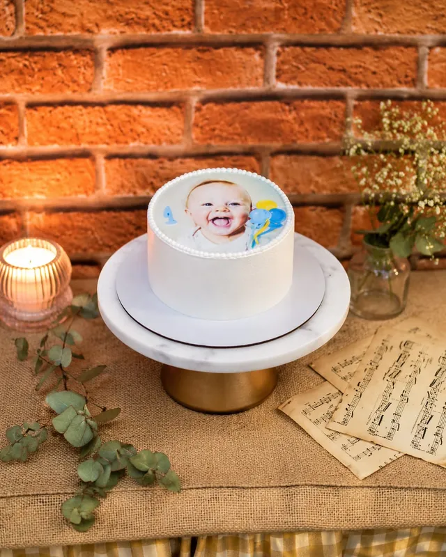 Bolo branco com foto comestível de bebê e borda de pérolas de açúcar