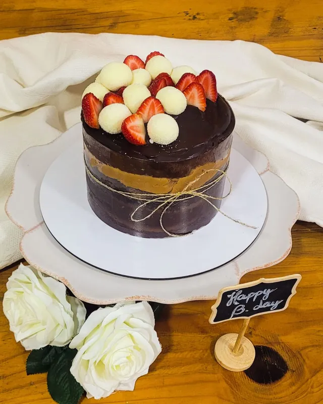 Bolo de chocolate com ganache, morangos e beijinhos no topo