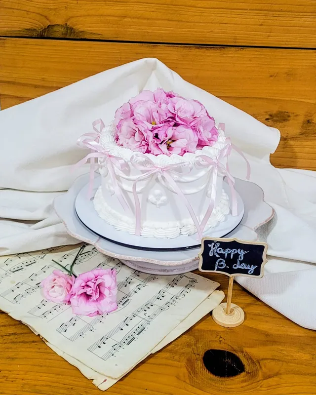 Bolo branco estilo vintage com laços de cetim rosa e lisianthus no topo