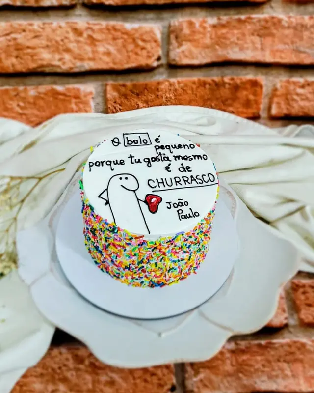 Bolo branco com confeites coloridos e dedicatória escrita à mão no topo